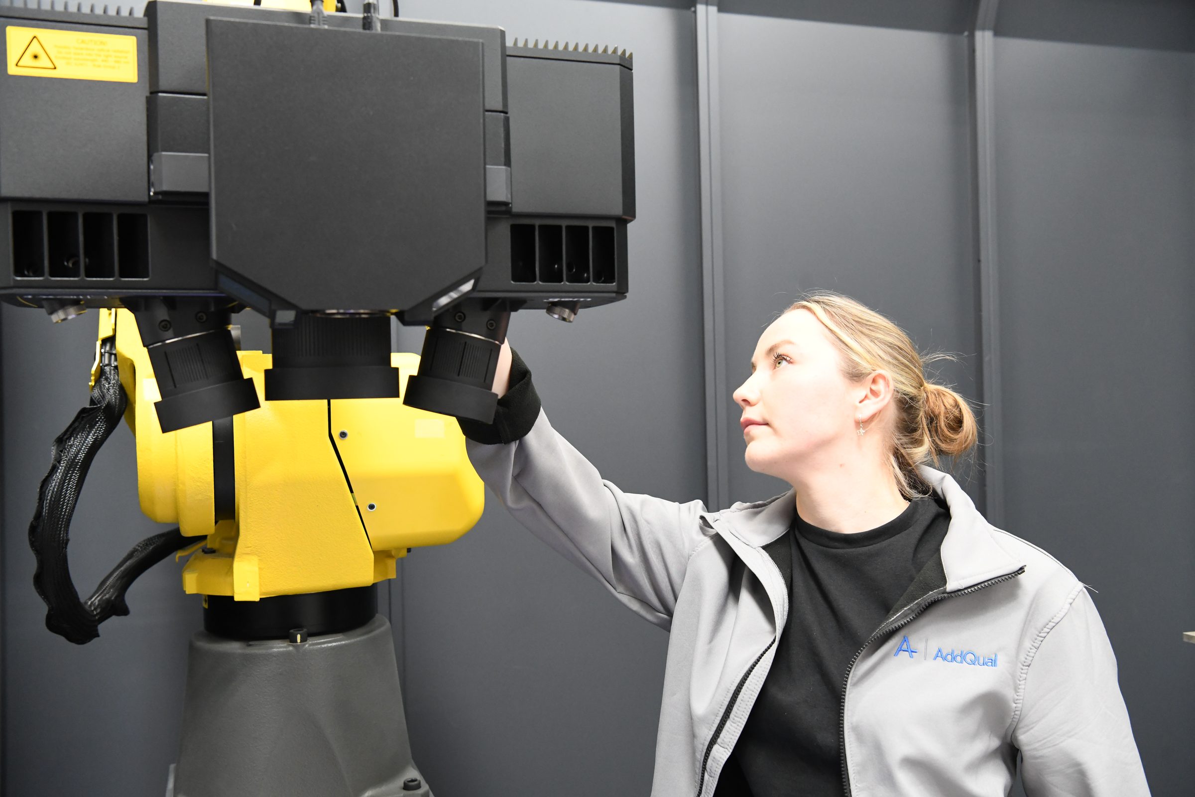 An AddQual engineer setting up a structured-light scanner head on a precision aerospace inspection cell.